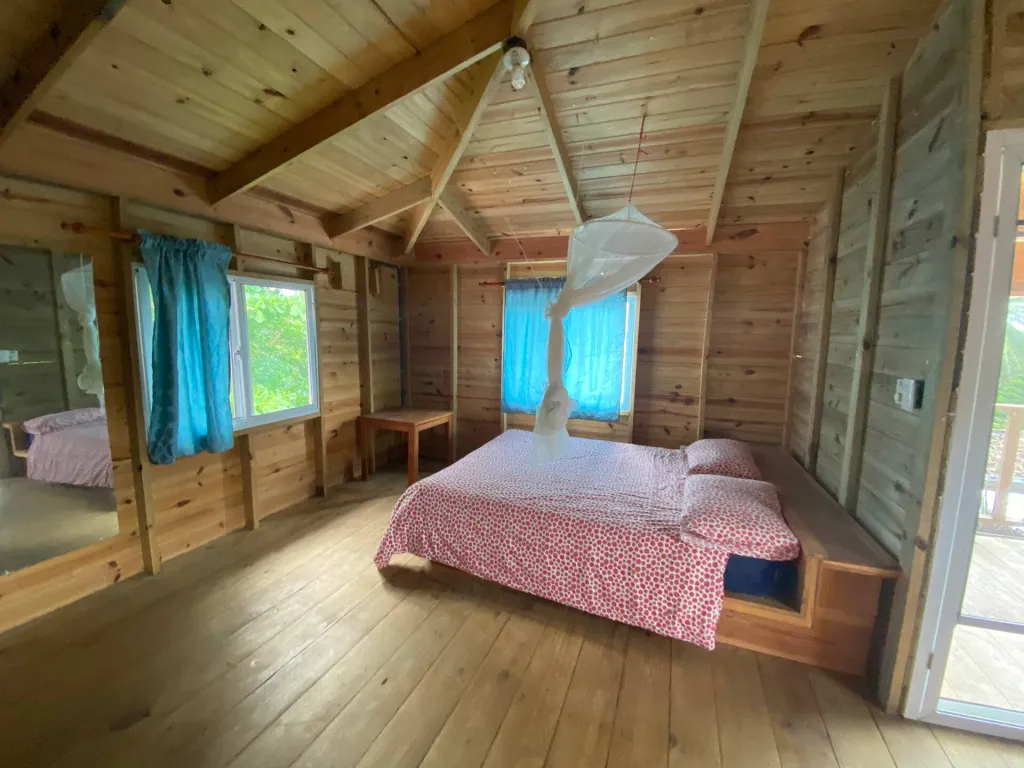 Wooden studio with a bed and a mosquito net