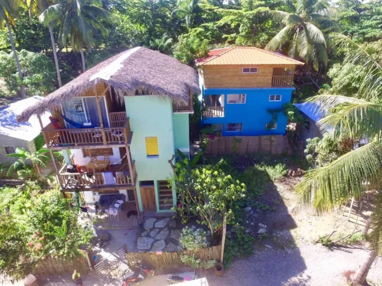 Two wooden houses with palm roofs and balconies seen from above