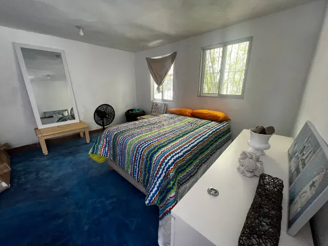 Bedroom with a striped bed cover and blue floor