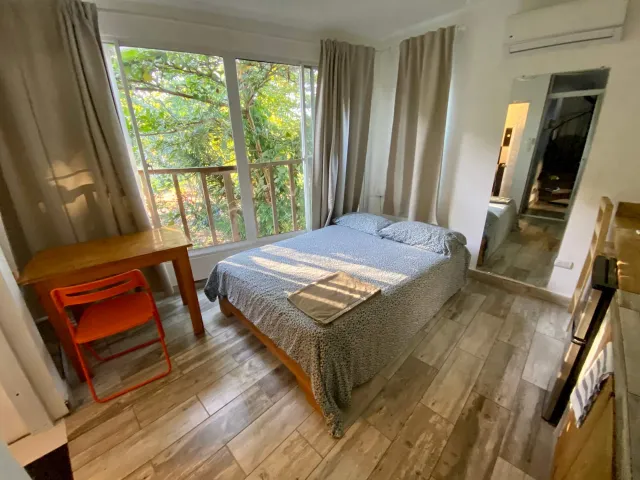 Bed by a big window and a small wooden balcony