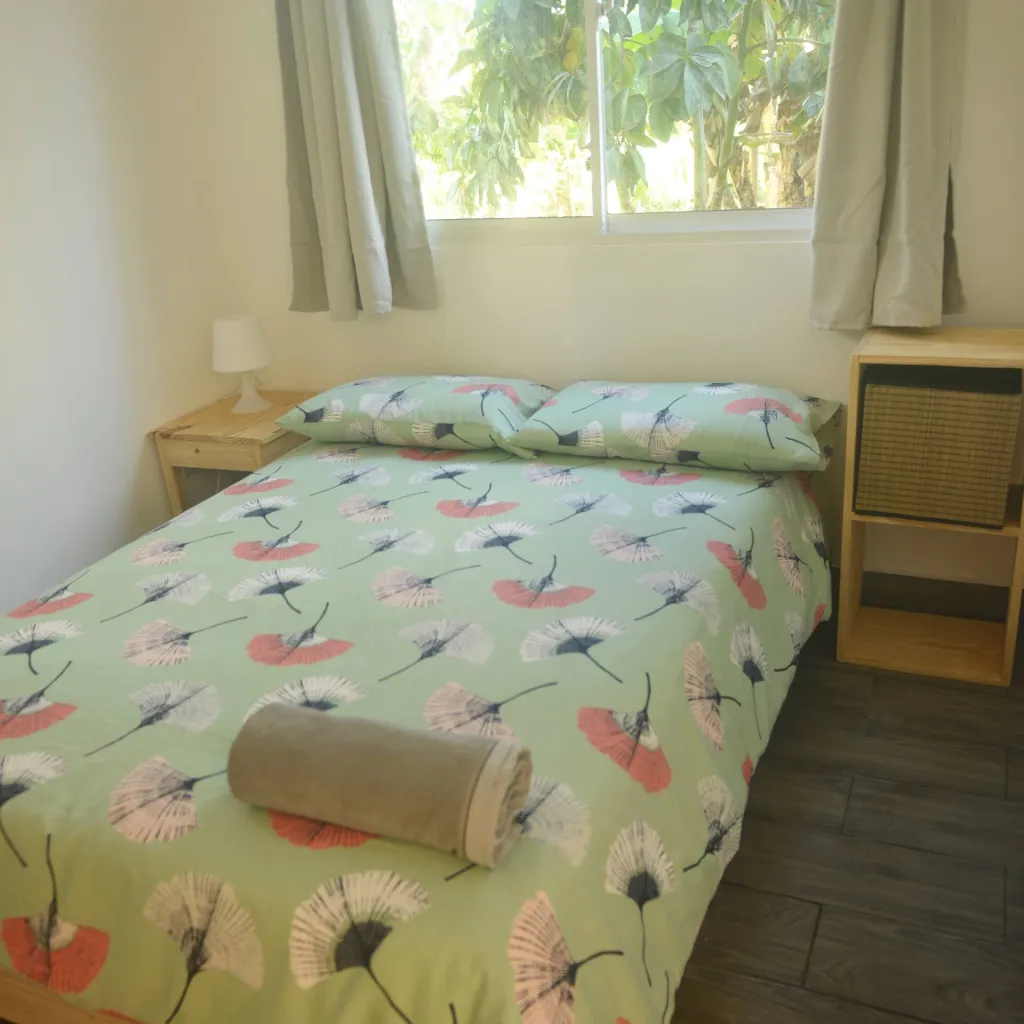 Double bed with a green flower cover by a window